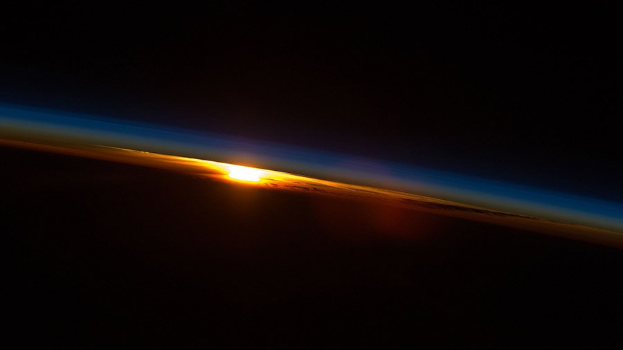 In this image from 2009, the sun sets below Earth and illuminates the sky as the space station orbits above the Indian Ocean coast of South Africa.